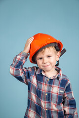 Portrait of cute little boy in a protective orange helmet over blue background.