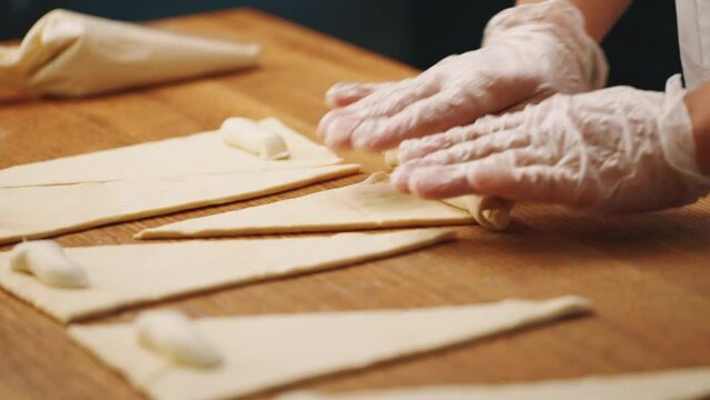 Woman making a croissant from dough in the kitchen