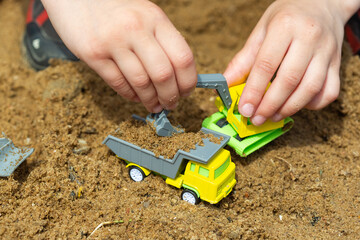 Bright colorful yellow green plastic toy truck in child hands