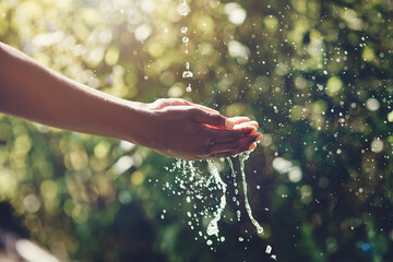 Refreshing splashes. Closeup shot of a man holding his hands under a stream of water outdoors.