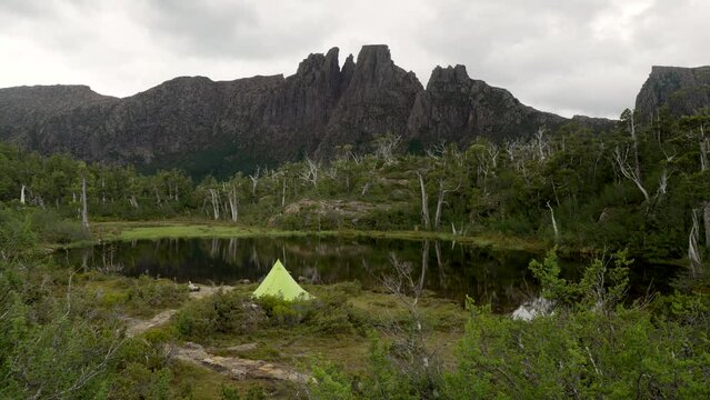 a green tent at the pool of memories of the labyrinth in cradle mountain-lake st clair national park of tasmania, australia, with mt geryon in the distance