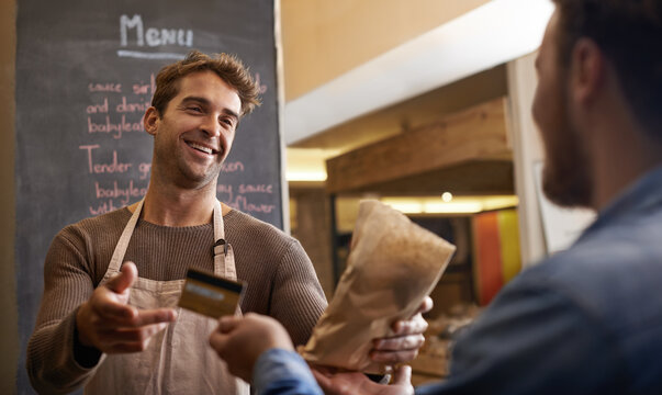 The Customers Keep Coming Back For More. Shot Of A Handsome Young Man Making A Sale At His Food Stall.