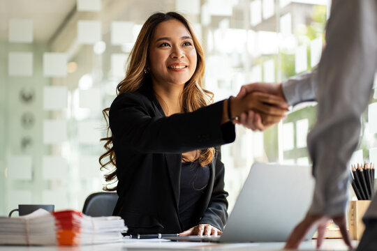 Shaking hands for a job interview of young Asian business woman in modern office. Greeting deal concept.