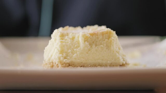 Asian boy about 5 years old eating cheese cake with a happy expression.