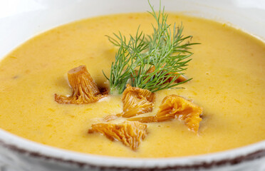 Cream soup with mushrooms chanterelles and herbs on black background