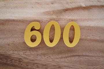 Golden Arabic numerals on a real brown and white wooden floor number 600