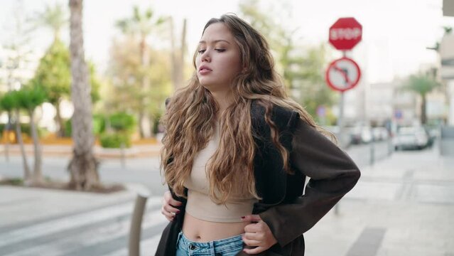 Young hispanic woman wearing jacket for cold standing at street