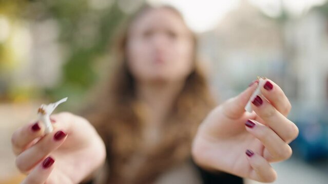 Young hispanic woman breaking cigarette at street