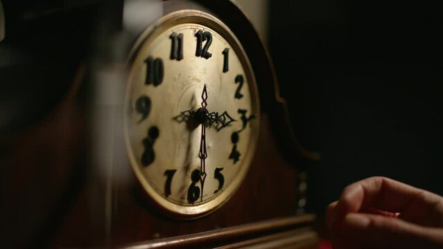 Hand changes time on an old mechanical clock.