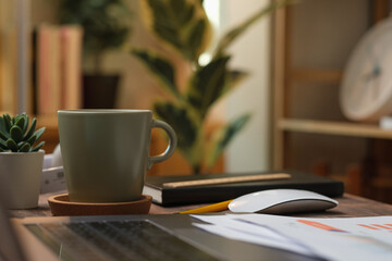 laptop with paperwork on wood table in living room at home.work at home