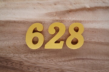 Golden Arabic numerals on a real brown and white wooden floor number 628