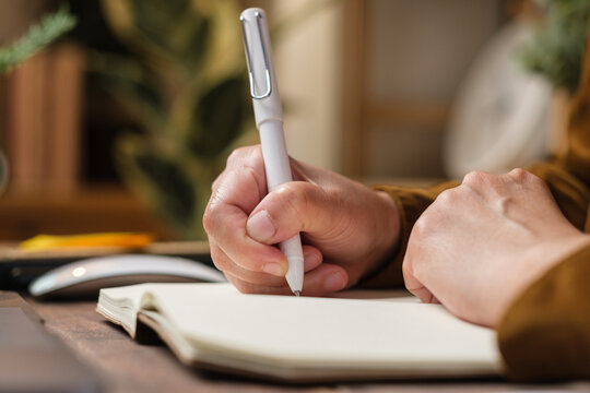 close uop woman hand writing on notebook at worknig desk at home