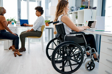 She never misses a day at the office. Shot of a businesswoman sitting in her wheelchair while working at her desk.