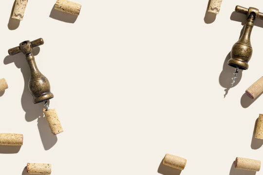 Wine corks and vintage corkscrew on beige background with shadows at sunlight. Minimal style layout with bottle cork, old bottle screw or opener, design concept for wine list, copy space