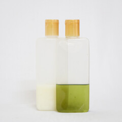 
bath products like shampoo and green oil in transparent bottles isolated in a white background