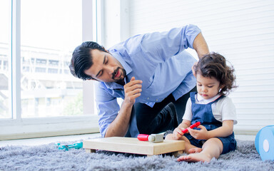 Obraz na płótnie Canvas Caucasian handsome father taking care, playing toys with his little cute daughter on floor in cozy living room at home after work with happiness. Family and Education Concept.