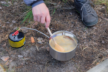 Soup in pot in the wild forest. Camping food making. Traveler foods for outdoor activities.