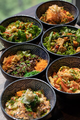 Poke bowls and other gourmet foods, with drinks and sushi on the table,