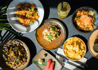 Poke bowls and other gourmet foods, with drinks and sushi on the table,