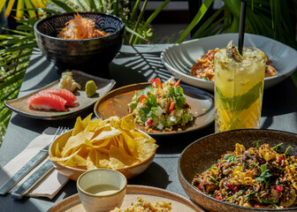 Poke bowls and other gourmet foods, with drinks and sushi on the table,