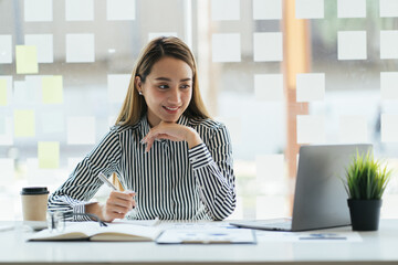 Young Asian businesswoman taking notes using a tablet at the modern office.