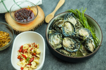 Raw oysters and side dishes in Thai style with spicy dipping sauce.