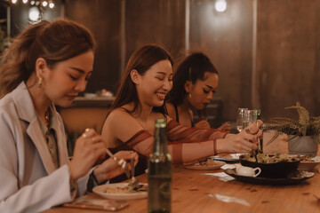 Young Asian friends eating and enjoying dinner together at outdoor restaurant. Friendship and reunion celebration