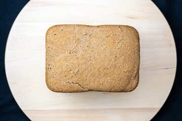 The freshly baked bread on a wooden board and black background close-up. Making bread. Top view.