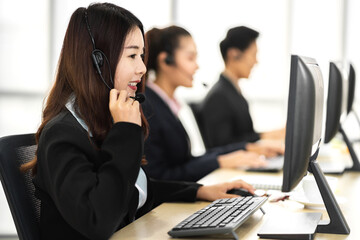 Group of happy call center smiling asian business operator customer help support team phone services agen working and talking with headset on desktop computer at call center office