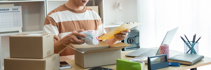 Online shopping concept the salesperson reading the product list while packing the product into the box