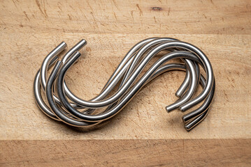 A group of Stainless Steel Hooks isolated on a wooden background. Hand ground and polished ready to...