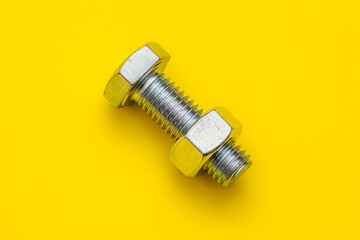 Bolt Nut abstract, isolated on a bright yellow background, threaded metal fastener. Workshop, manufacturing and building.