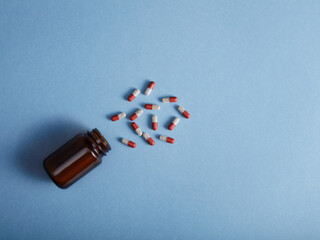 Pills spilling from a amber bottle, on blue paper background