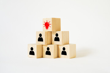 Obraz premium wooden cube block on pyramid sh ape , light on top ,concept for employees working together in teamwork, plan strategy and creating new ideas to improve and make successful business increasing revenue