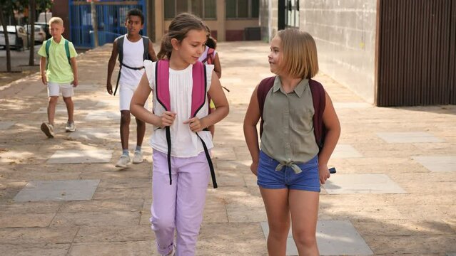 Modern confident tweens walking along city street on sunny summer day . High quality 4k footage