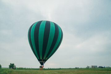 Inflating, unpack and flying up hot air balloon watermelon. Burner directing flame into envelope. Take off aircraft fly in morning blue sky. Start hot air burning to inflate gas fire to air balloon.