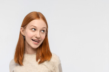 Close up portrait of Red-haired teenage girl looking to side playfully showing tongue. Cute teenage girl woman face closeup portrait with healthy clean skin isolated on white background. Copy space.