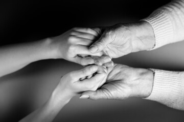 Mother and daughter holding hands. Close-up. Flat lay. Black and white colors. The concept of caring for pensioners