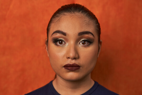 Hispanic Model with orange blackground with make up