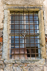 Fototapeta na wymiar morbider Charme - schmiedeeisernes Fenstergitter mit Herz im Bruchsteinmauerwerk eines alten Hauses.