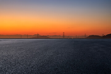 Asphalt road platform and mountain with high voltage power tower scenery at sunrise