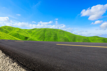 Empty asphalt road and green mountain nature scenery under blue sky