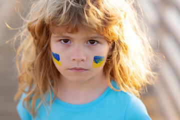 Ukraine flag on kids cheek. Protect save ukrainian children. No war, stop war, russian aggression. Little ukrainian patriot.