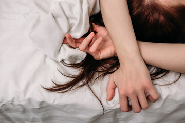  Sensual hands of a woman lying in bed on white sheets