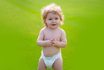 Cute baby in diaper on green grass in summertime. Funny little kid on nature. Happy Childhood. Baby...