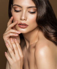Beauty Model Face Make up with Beige Lipstick and Perfect Eyeliner. Woman Skin and Lips Care Cosmetics. Women Hands with Nude Nail Polish over Brown Background - 492505383