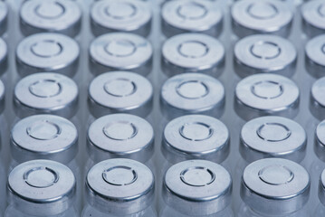 Glass medical ampoule vial for injection. Medicine is dry white drug penicillin powder or liquid with of aqueous solution in ampulla. Close up. Bottles ampule with aluminum cap on backgrounds gray.