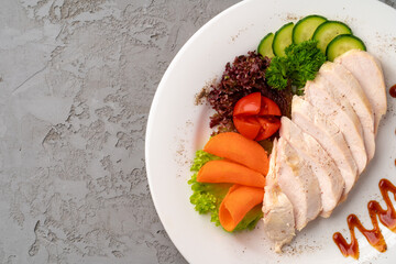 Roast chicken fillets and vegetables on gray background
