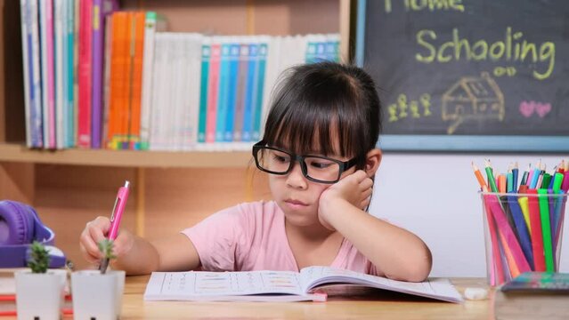 Cute little girl with headphones listening to audiobooks and looking at English learning books on the table. Learning English and modern education