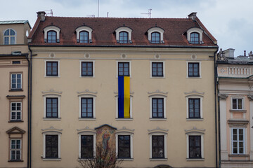 Fototapeta premium 09-03-2022. krakow-poland. Buildings in the main square of Krakow - Rynek Główny. Presenting the Ukrainian flag as identification with the Ukrainians in the Russo-Ukrainian War